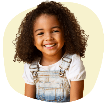 Safer for Kids Little girl smiling wearing overalls on yellow background shape